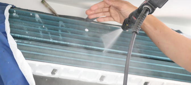 Técnico realizando a limpeza da serpentina de um ar condicionado split com jato de água, mostrando como limpar o ar condicionado corretamente