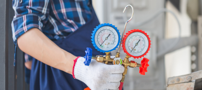 Técnico de ar-condicionado utilizando manômetro para medir pressão do sistema de climatização durante manutenção preventiva.