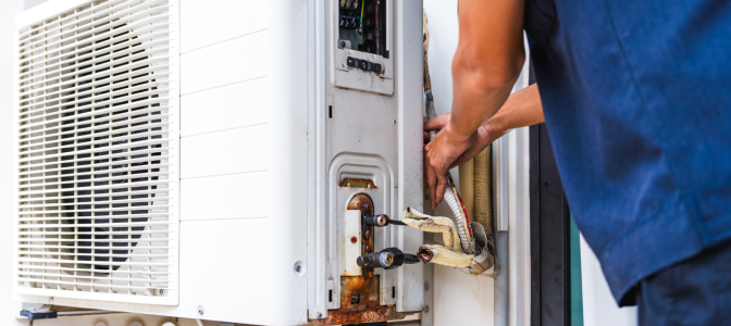 Técnico realizando instalação e manutenção em equipamento de ar-condicionado, representando sistemas VRF para empresas